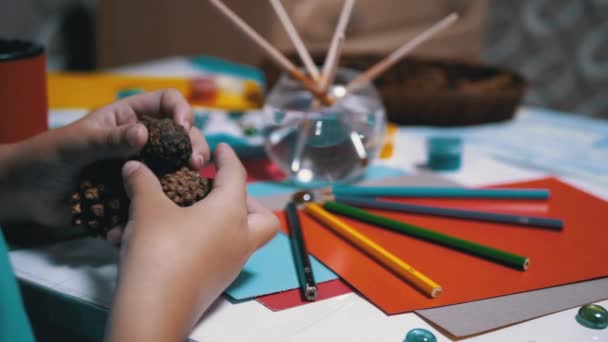 Talentoso niño sostiene conos de pino en manos y lápices de colores. Aprendizaje online - Metraje, vídeo