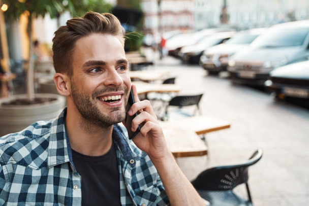 Young handsome man talking on the phone outdoors in the street - Фото, изображение
