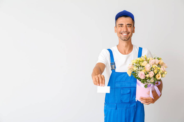 Delivery man with bouquet of flowers and business card on light background - Photo, Image