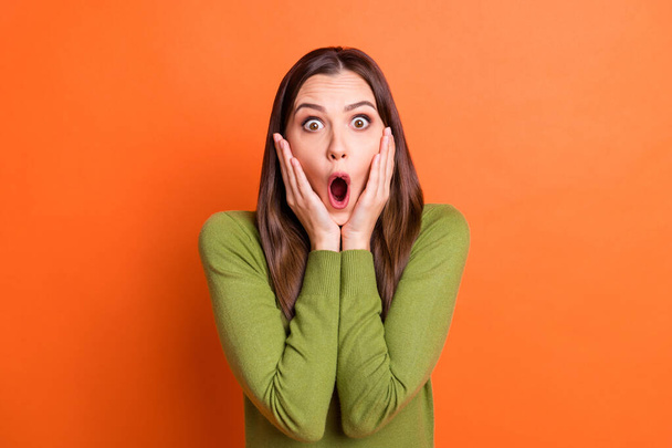 Portrait of young attractive shocked amazed surprised afraid girl with open mouth hold hands cheeks isolated on orange color background - Foto, immagini