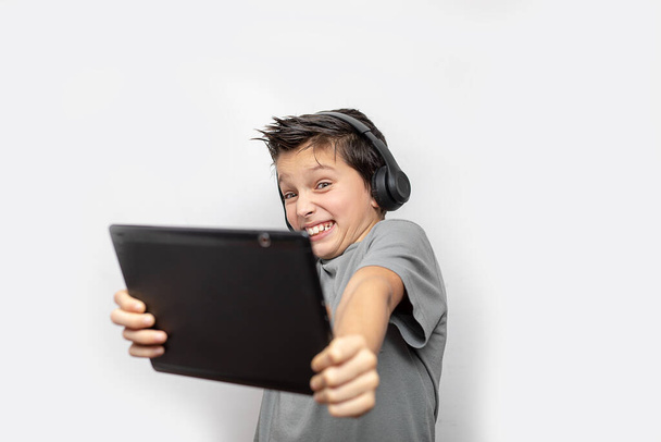 Shocked kid school teenage boy with digital tablet. Shouting and shocking, using tablet, headphones. Close-up studio shot isolated on white. - Foto, afbeelding