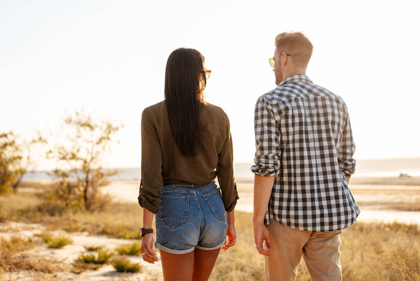 Beautiful young couple talking while strolling on nature at summer - Foto, Bild