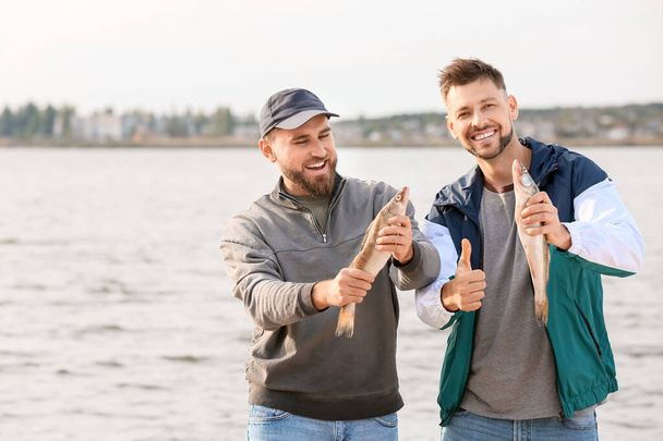 Ευτυχισμένοι νέοι άντρες που ψαρεύουν στο ποτάμι - Φωτογραφία, εικόνα