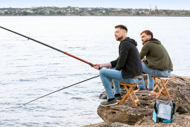 Jonge mannen die op de rivier vissen - Foto, afbeelding