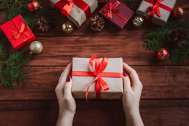 Woman gives beautiful gift box with red bow. Christmas concept. - Photo, Image