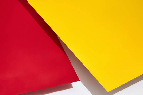 Red and yellow shadow-casting sheets of paper or stands above white surface. Advertising, branding area. Close up, copy space - Fotó, kép