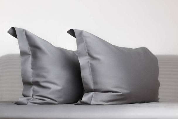 Two gray feather pillows on the bed. - Фото, изображение