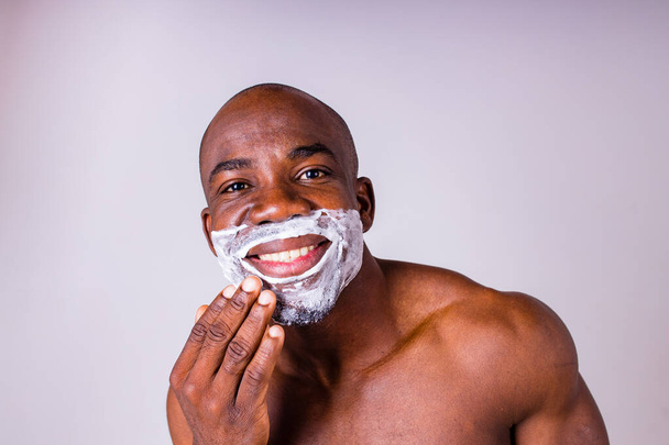 Латиноамериканец с бритвой и пеной для бритья на лице студия белый изолированный фон - Фото, изображение