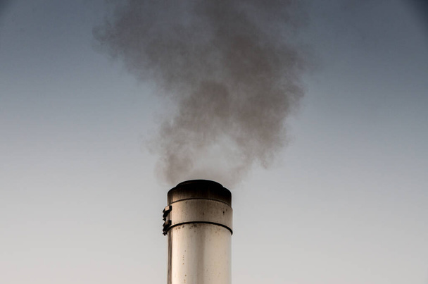 Курение трубы из нержавеющей стали перед утренним небом - Фото, изображение