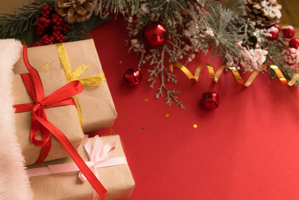 Krásná vánoční kompozice s dárkovou krabicí svázaná stuhou, dárky, Santa klobouk a jedle větve na červeném pozadí. Byt ležel s kopírovacím prostorem. - Fotografie, Obrázek