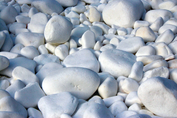 Bílý velký a malý kámen, rozdrcený kámen. Krásné a hladké rozptýlené na povrchu zblízka. Jako pozadí - Fotografie, Obrázek