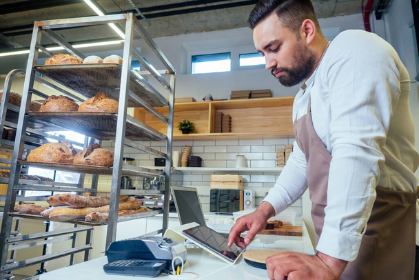 Handsome baker in uniform at the manufacturing small business owner concept - Foto, afbeelding