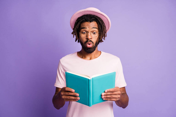 Foto de joven africano sorprendido hombre guapo hombre guapo espera leer diario azul aislado sobre fondo de color violeta - Foto, imagen