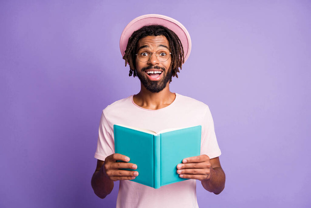 Photo of young african handsome smiling cheerful happy man male guy hold blue notebook isolated on purple color background - Valokuva, kuva