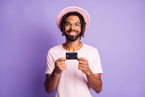 Photo portrait of man holding plastic card in two hands isolated on vivid purple colored background - Foto, immagini