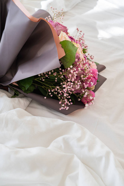there is a bouquet of flowers on the bed - Фото, изображение