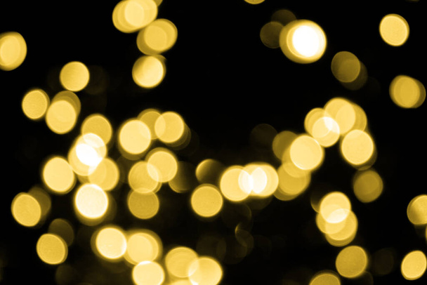 Defocused bokeh christmas big gold lights on black background. Abstract blurred gold glitter texture. Gold bokeh glitter wallpaper for Christmas, New year or festival background. - Foto, imagen