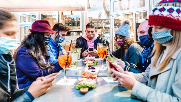 Milenyal arkadaşları kokteyl barında cep telefonu kullanıyor - salgın sırasında temas takip uygulamalarını kontrol eden yeni normal teknoloji konsepti - merkezdeki adama odaklı parlak filtre - Fotoğraf, Görsel
