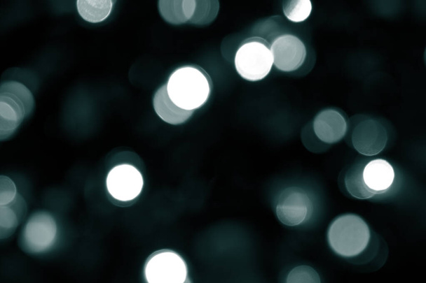 Tidewater Green colors. Defocused bokeh christmas white lights on dark green background. Blurred abstract green glitter texture. Green bokeh glitter wallpaper for Christmas, New year or festival background.  - Foto, Imagen