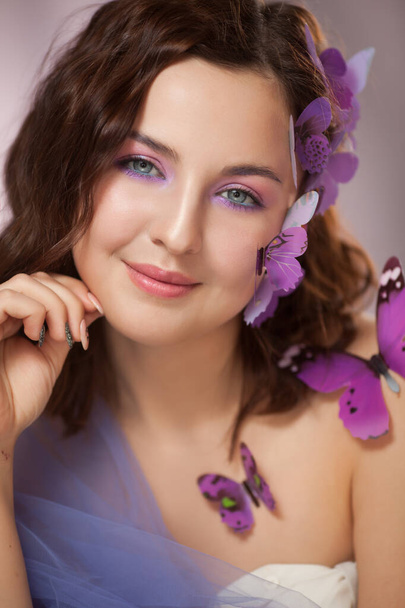 Beautiful young woman with artificial butterfly in curly hair. - Foto, imagen