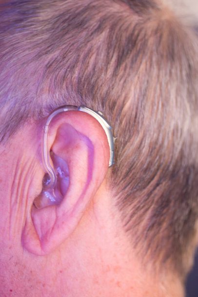Hombre anciano blanco caucásico que usa audífono digital moderno en la oreja con cabello gris. - Foto, Imagen