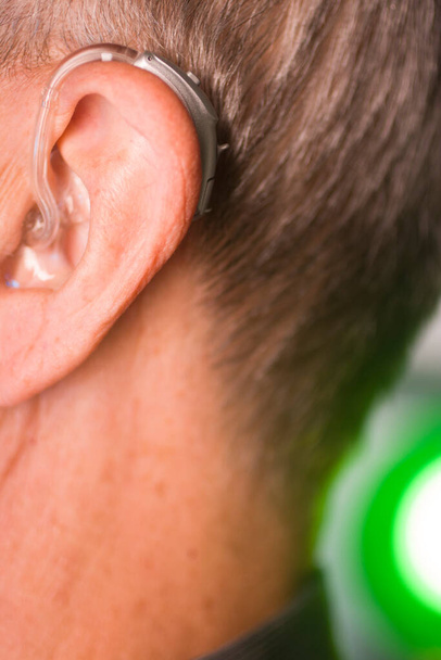 Kaukasischer weißer alter Mann mit modernem digitalen Hörgerät im Ohr und grauen Haaren. - Foto, Bild