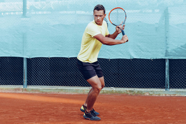Young handsome man playing tennis on the tennis court - Fotó, kép