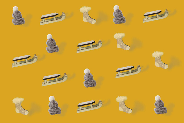Wollmütze mit weißem Bommel, Schlitten und Sockenornament auf Fortuna Gold Hintergrund - Foto, Bild