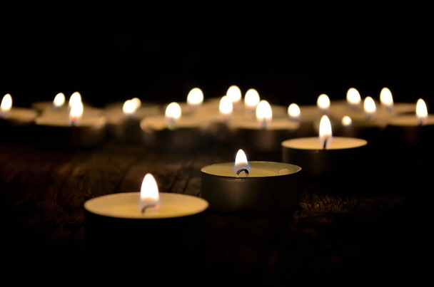 Many small christmas candles burning at dark. Shallow depth of field, selective focus - Photo, Image