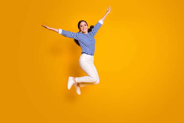 Full size photo of cheerful girl jump hold hand imagine she fly wings plane after spring discounts wear good look clothes isolated over bright color background - Foto, Bild