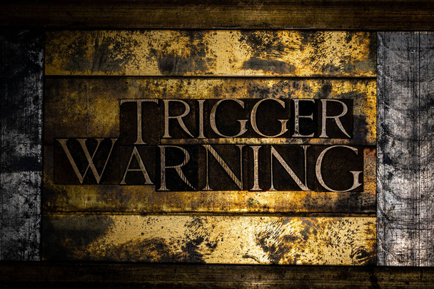 Trigger Waarschuwing tekst op grunge getextureerd koper en goud achtergrond - Foto, afbeelding