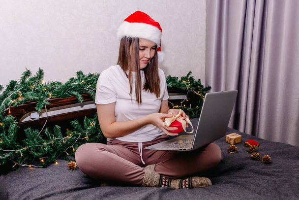 a young happy brunette wishes her family and friends a happy new year and Christmas over the Internet using a laptop. - Fotoğraf, Görsel
