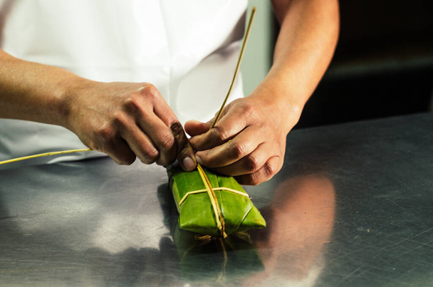 Peruvian hands tying a traditional tamale with banana leaves. - Photo, Image