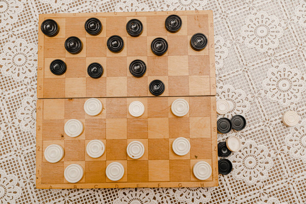 Brown wooden chessboard with classic checkers. Table game. Checkers on playing field for the game. - Фото, изображение