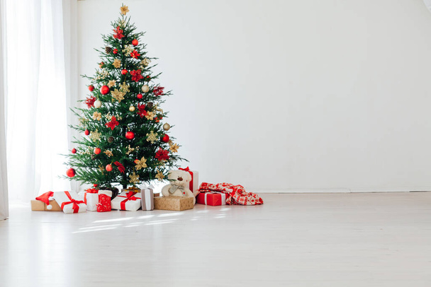Grande árvore de Natal bonita decorada com belas bugigangas brilhantes e muitos presentes diferentes no chão de madeira. - Foto, Imagem