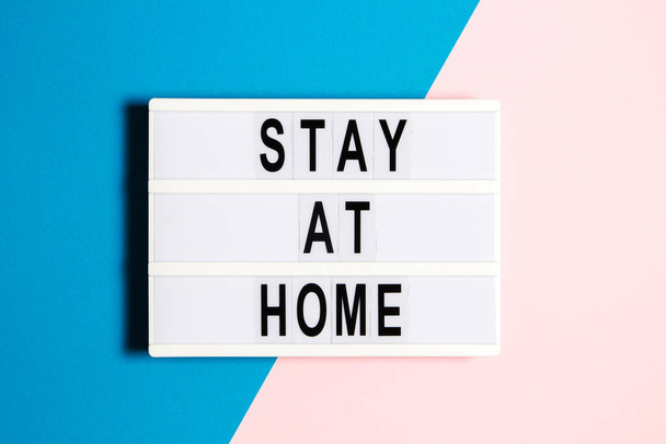 Lightbox con texto Quédese en casa sobre fondo rosa y azul. Atención médica, concepto de cuarentena - Foto, imagen