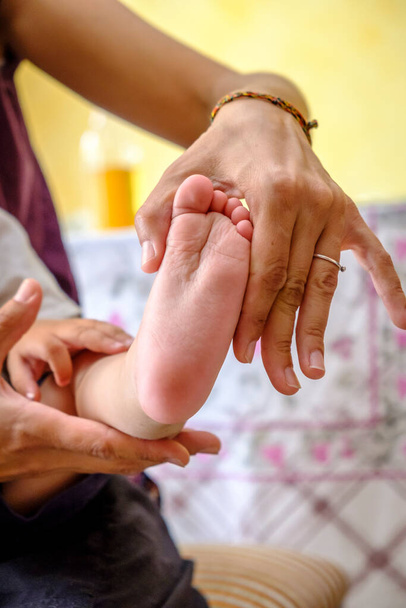 Die Hand einer Frau hält den kleinen Fuß eines Babys. - Foto, Bild