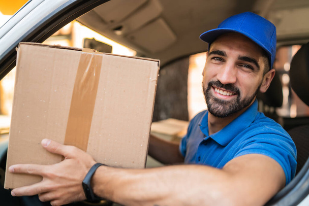 Delivery man holding cardboard boxes in van. - 写真・画像