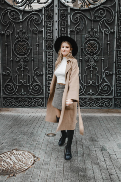 blonde in brown coat with a black hat posing, smiling, upset - Zdjęcie, obraz