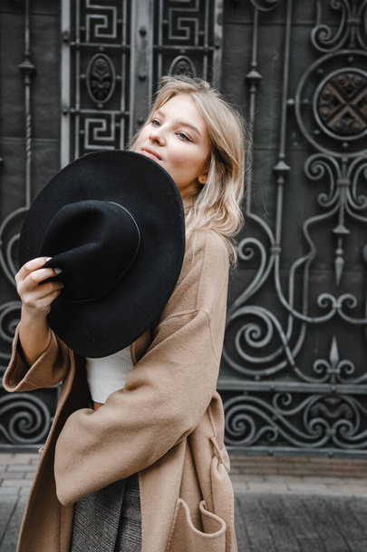 blonde in brown coat with a black hat posing, smiling, upset - Photo, image