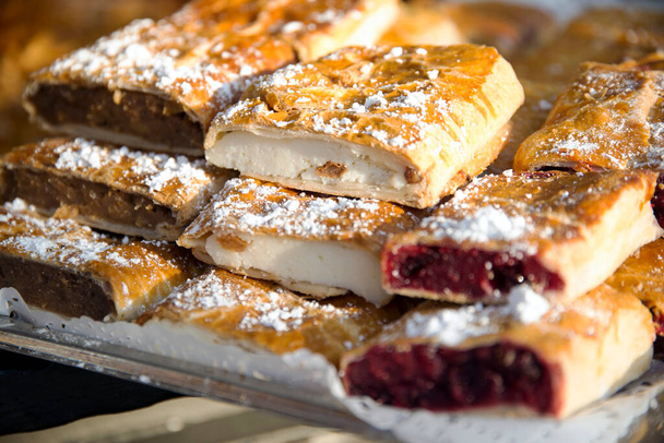 Homemade strudels with  various flavor for sale at christmas market outdoors. Fresh homemade cakes stuffed with various filling. Serving domestic natural food. Home made strudels on old traditional way - Photo, Image