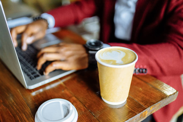african american man getting online education and drinks coffee to go frop paper eco cup - Photo, Image