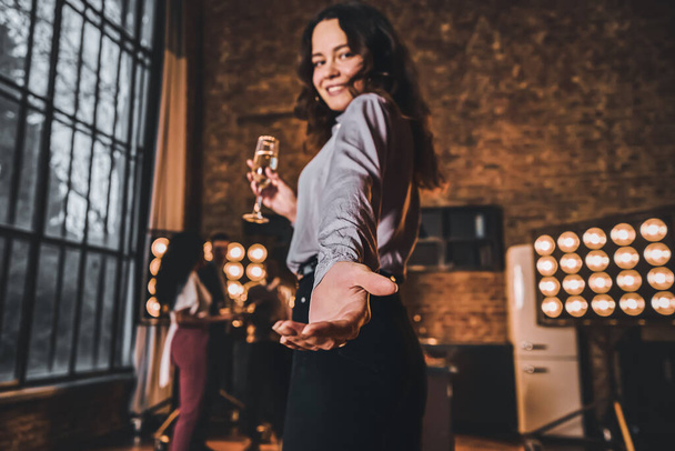 Low angle view of pretty woman holding a glass of champagne and holding out her hand in front of her. Home party concept - Fotoğraf, Görsel