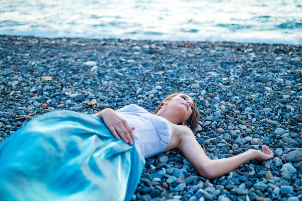 Beautiful long haired woman dressed a mermaid sitting on the sand beach background - Zdjęcie, obraz
