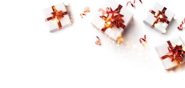 Joyeux Noël carte faite de boîtes-cadeaux de Noël avec des arcs rouges, décoration rouge sur fond blanc. Bannière de Noël et Nouvel An avec bokeh, lumière, paillettes. Couché plat, vue du dessus - Photo, image