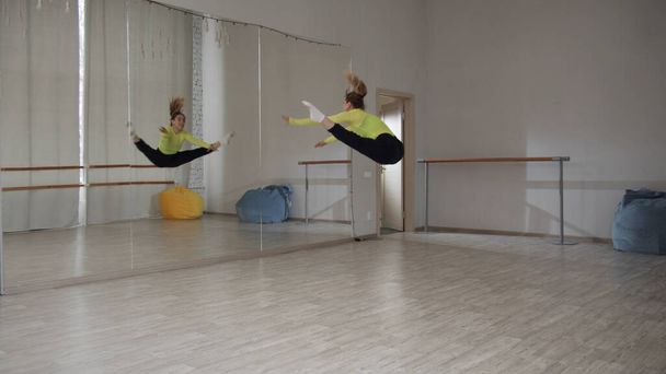 Nowoczesny taniec z elementami akrobacji, młoda dziewczyna skacze i tańczy w holu przed lustrem - Zdjęcie, obraz