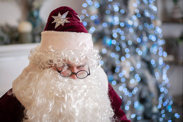 Detailní portrét Santa Clause, zimní sváteční charakter s brýlemi a obrovským kudrnatým vousem, jasně červený kostým na Vánoce a Nový rok. - Fotografie, Obrázek