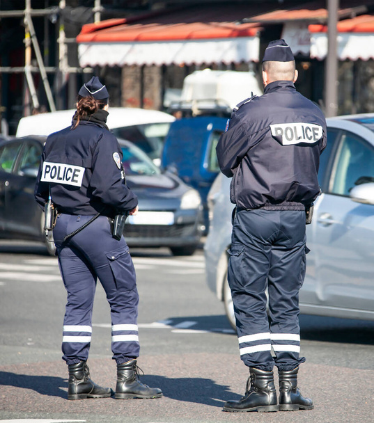 Twee politieagenten op straat controleren het verkeer van auto 's. Politieagenten, een man en een vrouw met speciale uitrusting, monitoren het verkeer op de weg.  - Foto, afbeelding