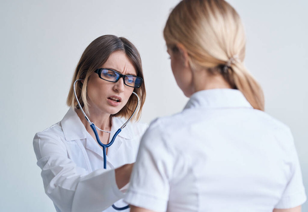 Ärztin im Arztkittel und Brille blaue Stethoskoppatientin - Foto, Bild