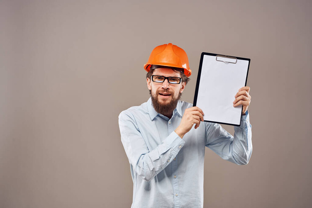 Un hombre con una camisa con un sombrero naranja ingeniero documentos de trabajo prestación de servicios - Foto, imagen